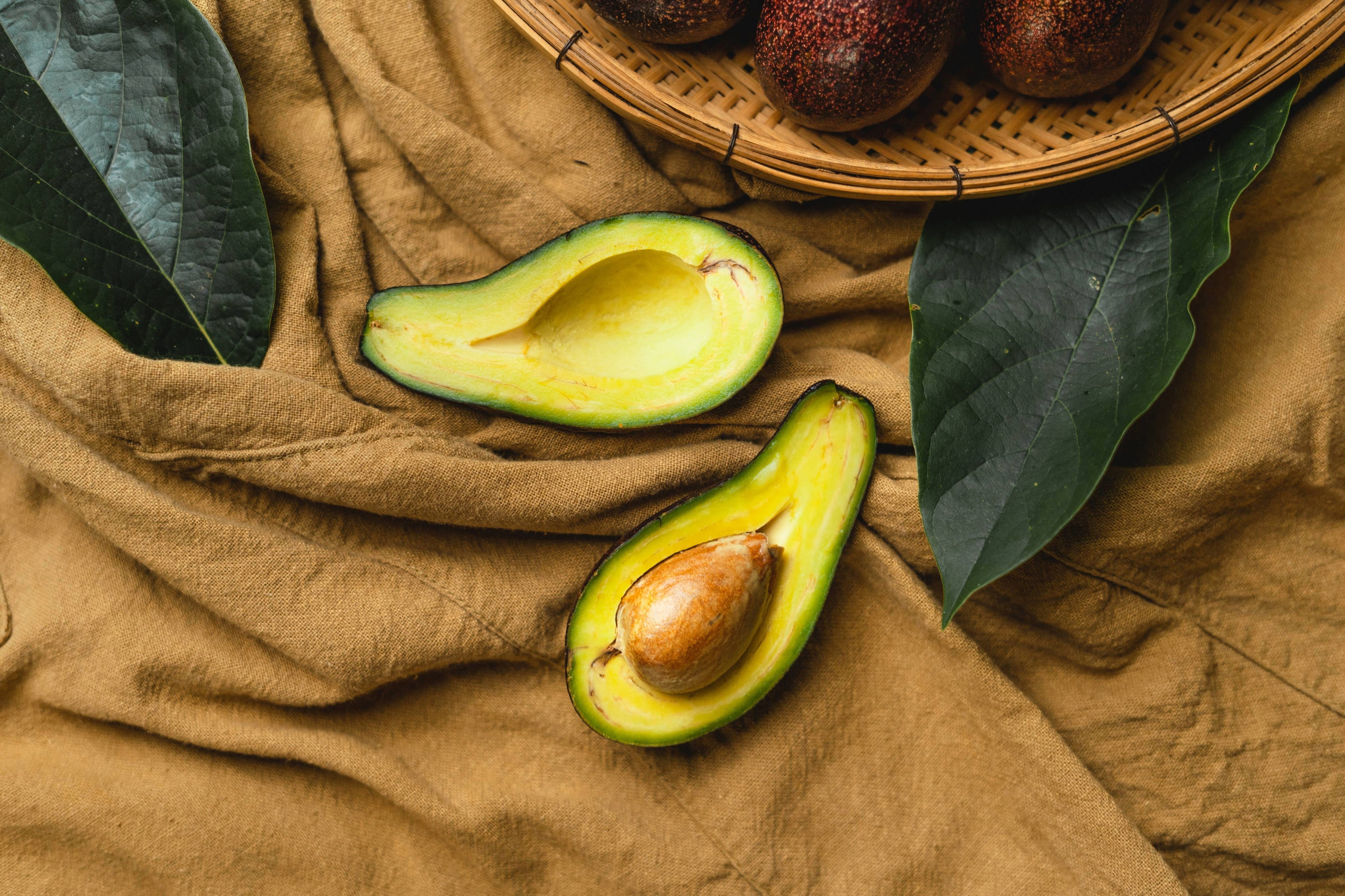 halved avocado on a natural linen surface, photographed in warm soft light.
